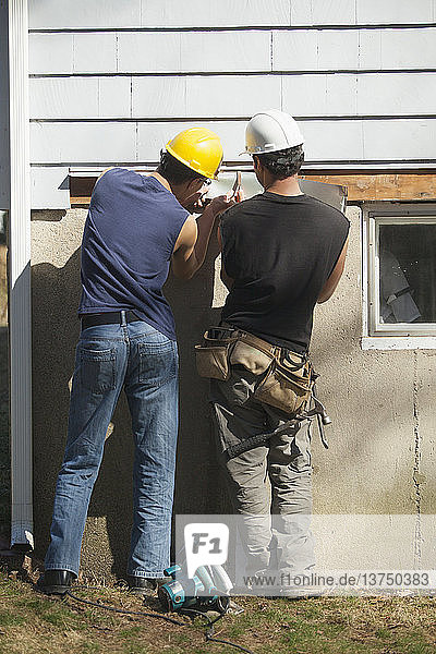 Spanische Zimmerleute  die Abdeckungen unter den Schindeln eines Hauses anbringen