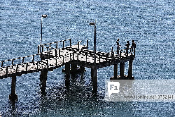 Junge Männer auf einer Seebrücke.