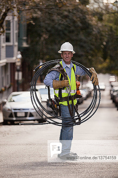 Cable installer carrying video cables on a street