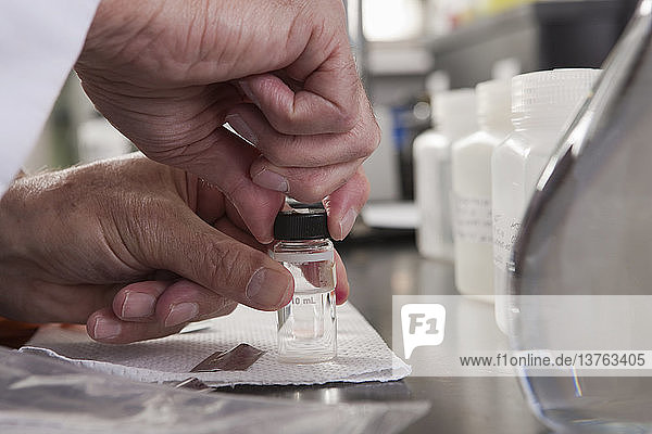 Wissenschaftler versiegelt Probenflaschen nach der Zugabe von Chemikalien im Labor einer Wasseraufbereitungsanlage
