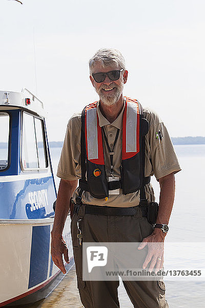 Porträt eines Ingenieurs für öffentliche Arbeiten  der lächelnd neben einem Wartungsboot steht