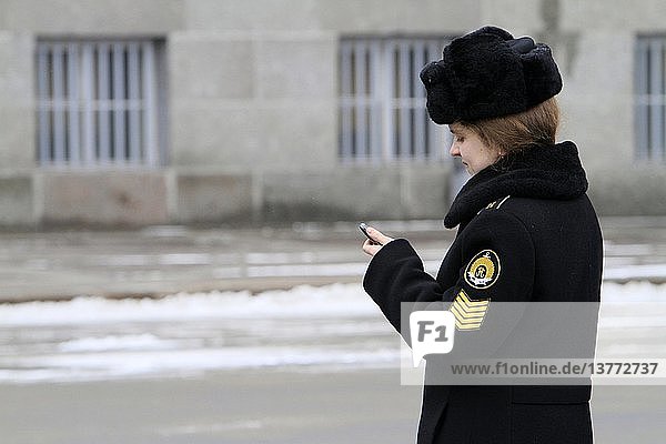 Russische Frau  die ihre Texte auf dem Handy überprüft.