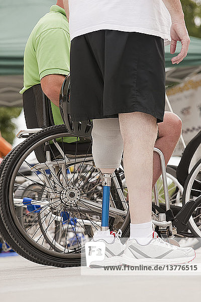 Man with prosthetic leg standing with a man in wheelchair with spinal cord injury