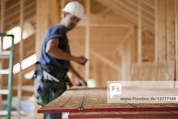 Ein spanischer Zimmerer knüpft eine Schnur an einer Dachplatte eines im Bau befindlichen Hauses