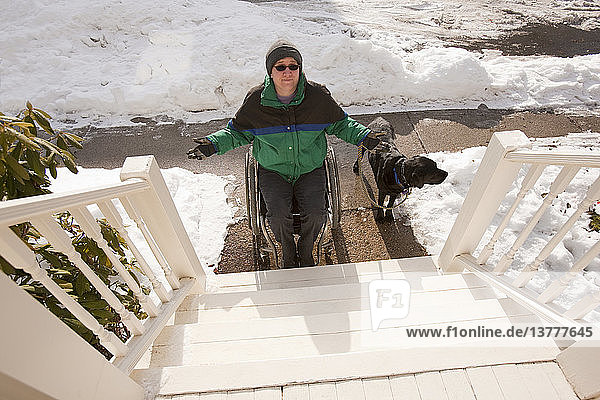 Frau mit Multipler Sklerose versucht  mit einem Diensthund eine Treppe hinaufzusteigen