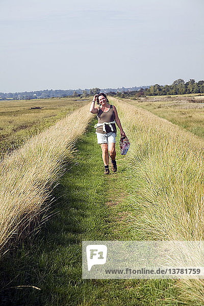 Frau beim Spazierengehen am Hochwasserschutzufer  Fluss Deben  Sutton  Suffolk