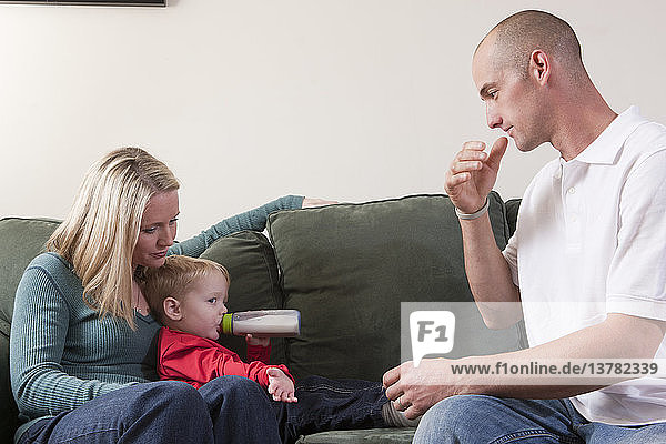 Mann gebärdet das Wort ´Drink´ in amerikanischer Zeichensprache  während sein Sohn Milch trinkt