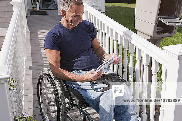 Mann mit Rückenmarksverletzung im Rollstuhl holt seine Post ab