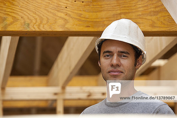 Hispanischer Zimmermann lächelt auf einer Baustelle