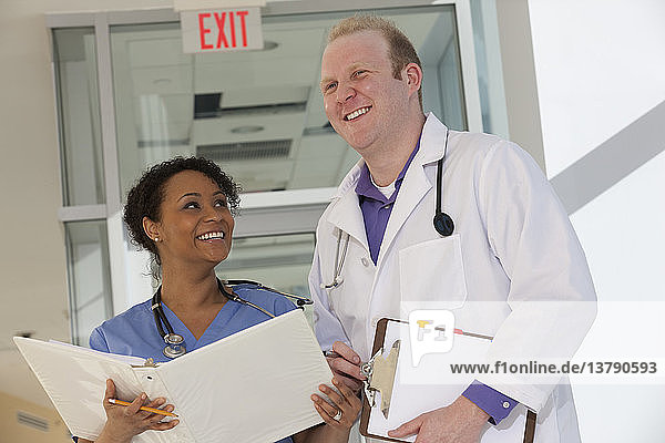 Male doctor discussing a medical report with a female nurse