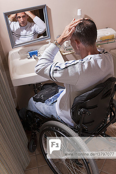 Mann mit Rückenmarksverletzung im Rollstuhl beim Frisieren seiner Haare