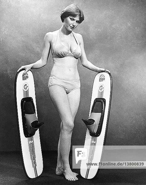 Vereinigte Staaten um 1964 Eine junge und attraktive Frau im Bikini hält auf einem Werbefoto ein Paar EP-Wasserskier.
