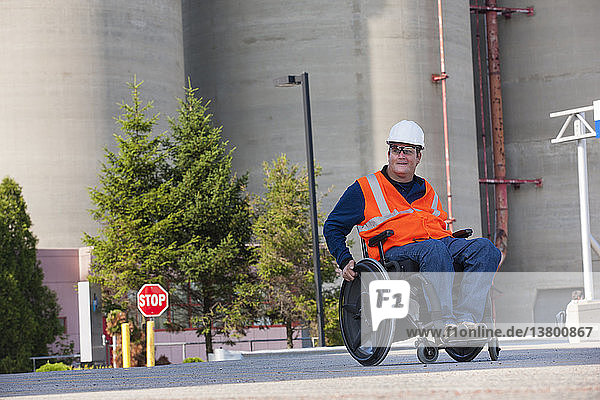 Techniker im Rollstuhl bei der Inspektion von Lagertanks im Freien