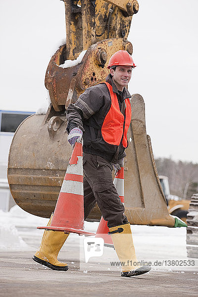 Verkehrsingenieur beim Verschieben von Verkehrsleitkegeln auf einer Baustelle