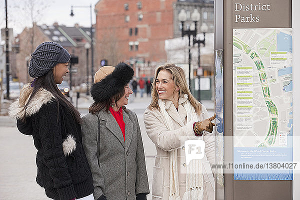 Brazilian woman studying a park map with her mother and grandmother  Boston  Massachusetts  USA