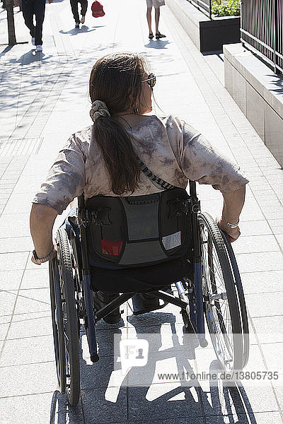 Frau mit Querschnittslähmung im Rollstuhl auf dem Bürgersteig  Boston  Massachusetts  USA