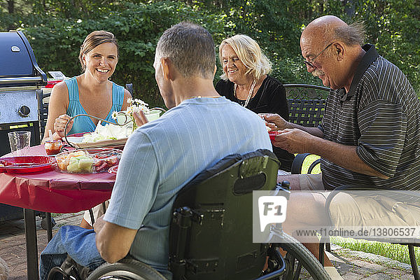 Mann mit Rückenmarksverletzung im Rollstuhl beim Familienpicknick mit den Großeltern