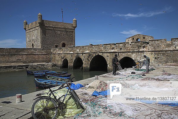 Männer arbeiten an Fischernetzen  die am Kai von Port Skala und der befestigten Brücke ausgelegt sind  Essaouira  Marokko