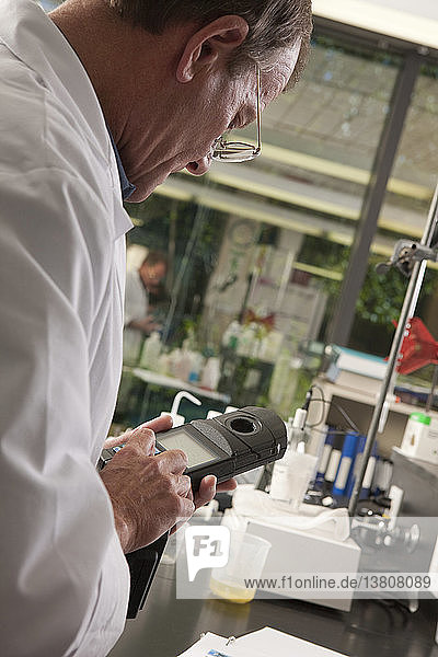 Wissenschaftlerin  die ein Messgerät im Labor einer Wasseraufbereitungsanlage benutzt