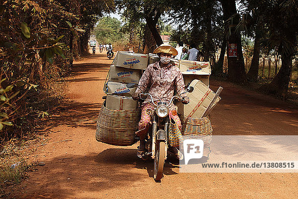 Frau transportiert Waren auf einer unbefestigten Straße
