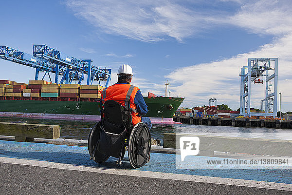 Transportingenieur im Rollstuhl bei der Inspektion eines Containerschiffs im Seehafen