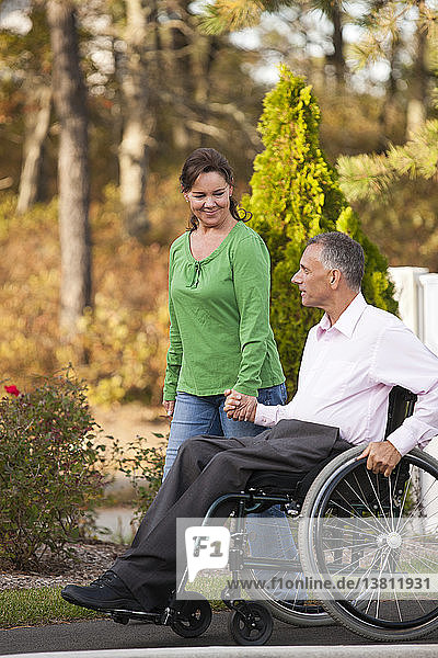 Frau benutzt Bürgersteig mit Ehemann im Rollstuhl mit Rückenmarksverletzung