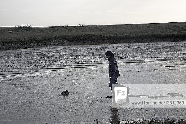 Junge  der im Schlamm und im Salzwasser spazieren geht  Shingle Street  Orford Ness  Suffolk  England