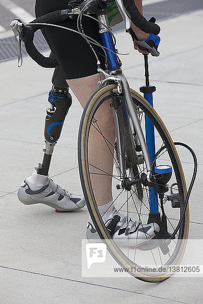 Frau mit einer Beinprothese pumpt Luft in ein Fahrrad