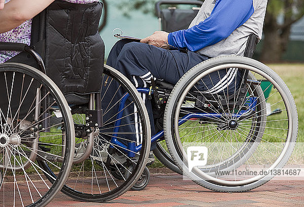 Ein Mann mit Multipler Sklerose und eine Frau mit einer Rückenmarksverletzung in Rollstühlen