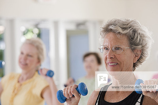 Senior women exercising with dumbbells in a health club
