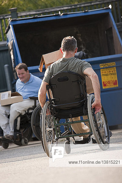 Männer in Rollstühlen bringen den Müll zur Mülltonne