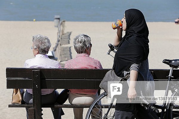 Sandstrand an der Nordsee  muslimische Frau trinkt eine Limonade.