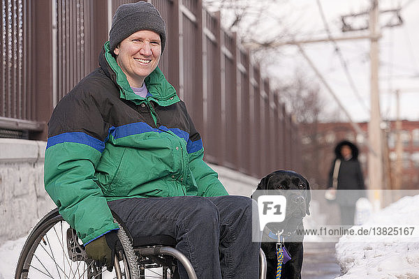 Woman with multiple sclerosis in a wheelchair with a service dog in winter snow