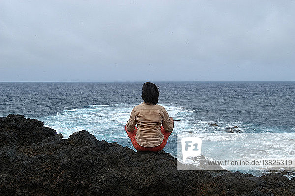 Meditierende Frau mit Blick auf den Atlantischen Ozean