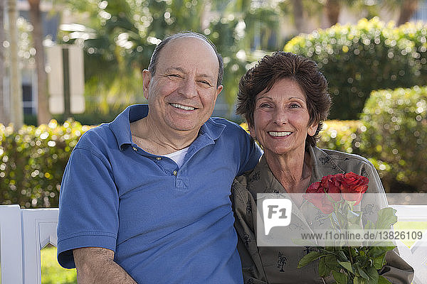 Porträt eines lächelnden älteren Paares mit einer Valentinsrose