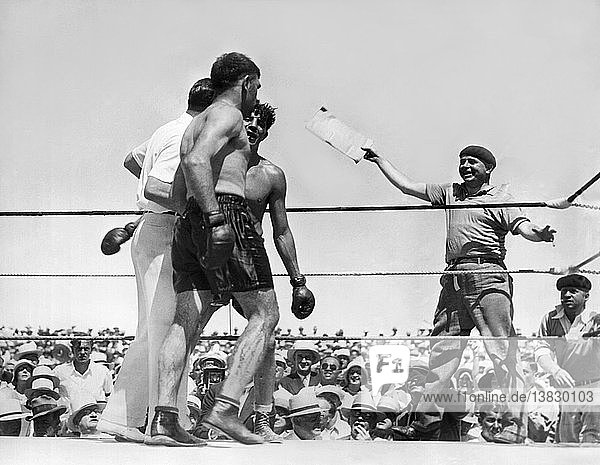 Reno  Nevada: 4. Juli 1931 Der Ringrichter und ehemalige Schwergewichts-Champion Jack Dempsey gibt Paulino Uzcudun nach einem zermürbenden Kampf über 20 Runden gegen Max Baer in der Sonne Nevadas den Zuschlag. Dempsey steht zwischen den beiden Kämpfern  wobei Baer mit dem