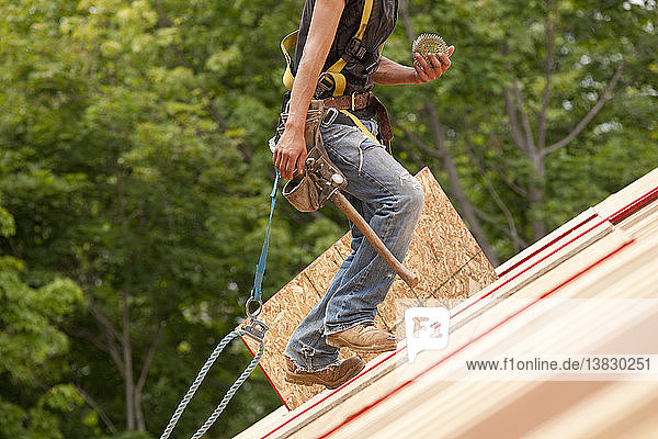 Spanischer Zimmermann  der auf dem Dach eines im Bau befindlichen Hauses Nägel aufwickelt