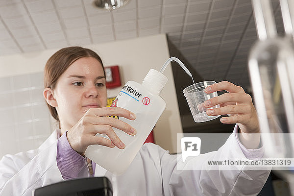 Wissenschaftler  der destilliertes Wasser in einen Probenbehälter im Labor einfüllt