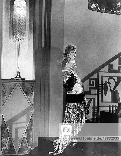 Hollywood  Kalifornien: ca. 1929 Der russische Filmstar Olga Baclanova modelliert ein Abendkleid aus goldenem Stoff  Pailletten  Kristallen und goldener Spitze. Dazu trägt sie einen goldenen  fingerlangen Mantel  der mit braunem Zobelpelz eingefasst ist.