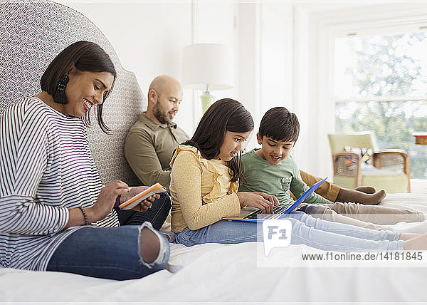 Family using technology on bed