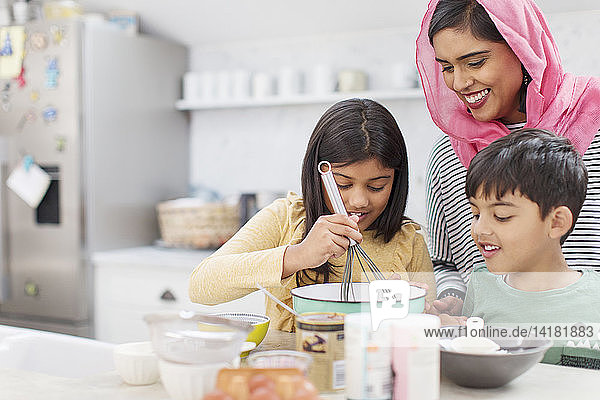 Mother in hijab baking with children in kitchen