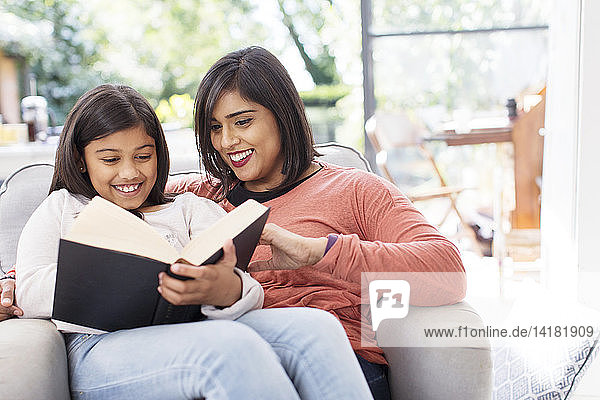 Mutter und Tochter lesen ein Buch im Sessel