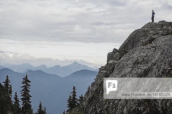 Männlicher Wanderer steht auf einem schroffen Berggipfel und betrachtet die Aussicht  Dog Mountain  BC  Kanada