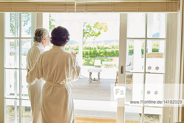 Älteres Paar in Bademänteln an der Terrassentür eines Hotels