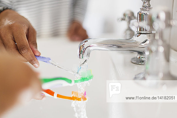 Nahaufnahme einer Familie beim Spülen der Zahnbürsten im Waschbecken