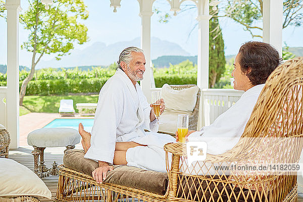 Älteres Paar in Bademänteln entspannt sich und trinkt Mimosen im Pavillon des Resorts