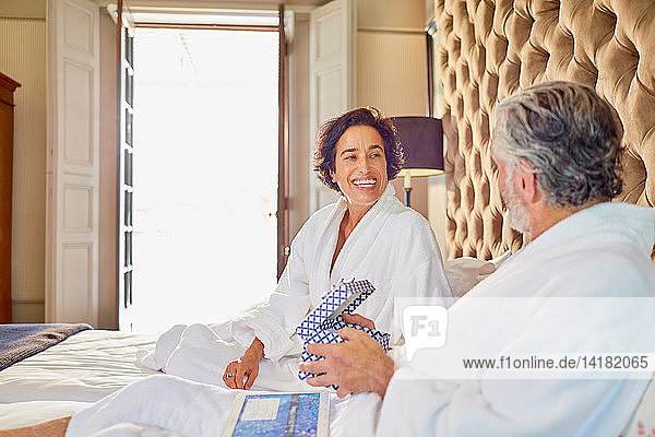 Happy mature couple in bathrobes on bed