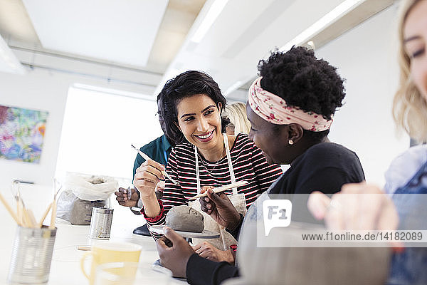 Women shaping clay in art class