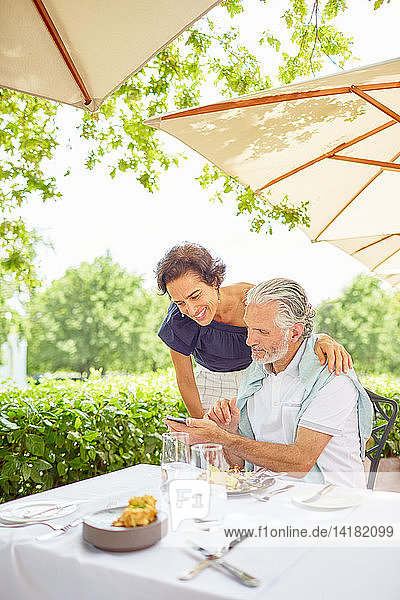 Älteres Paar mit Smartphone im Terrassenrestaurant