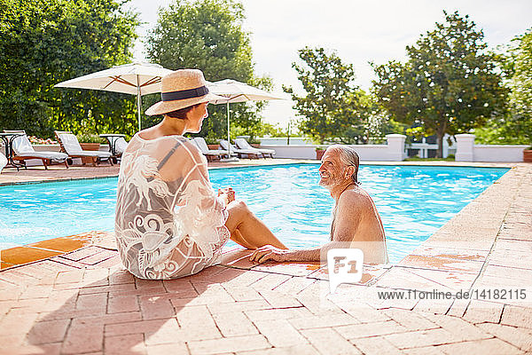 Glückliches reifes Paar entspannt sich am sonnigen Schwimmbad des Resorts